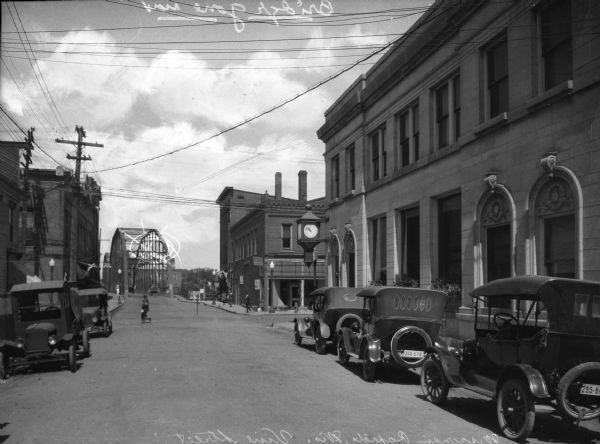 View down Vine Street. Automobiles are parked on either side of the street and Wood County National Bank stands to the right. A pedestrian crosses at the intersection.