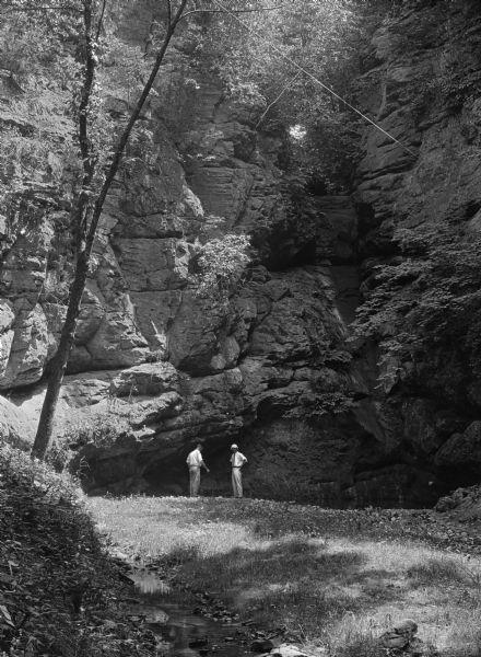 Two men stand near a geological formation in Mitchell's Glen, formerly owned by S. D. Mitchell.