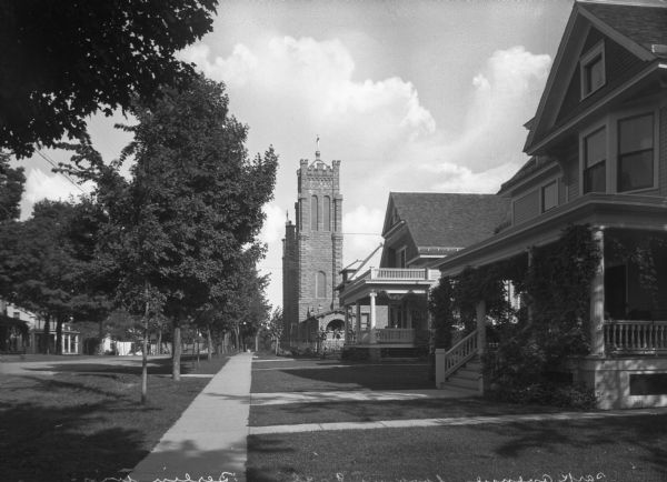 View down sidewalk on right side of Park Avenue, looking east. Saint Joseph's Church, built in 1853, is further down the street past houses with large porches. 