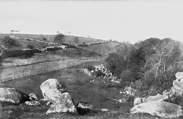 View of a park and Pigeon Hill.  A fence divides the hilly landscape.