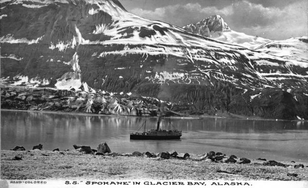 View of the S.S. "Spokane" on Glacier Bay. Mountains rise in the background. Caption reads: "S.S. "Spokane" in Glacier Bay, Alaska."