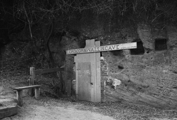 Entrance to the tourist attraction of Lord Cornwallis Cave. The sign above the door reads, "Admission 10¢." Initials are inscribed in the dirt wall.