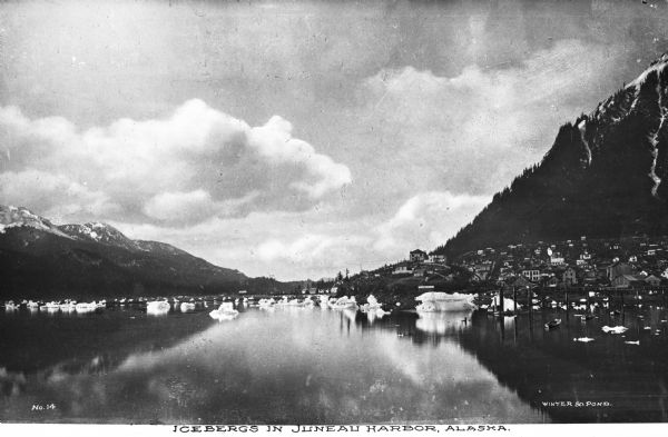 View of icebergs in Juneau Harbor. Mountains are beyond the harbor, and a city is on the left. Caption reads: "Icebergs in Juneau Harbor, Alaska."