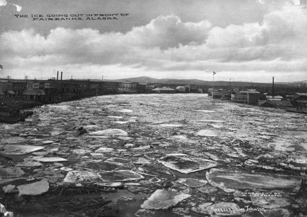 Elevated view of a river full of ice chunks. Caption reads: "The ice going out in front of Fairbanks, Alaska."