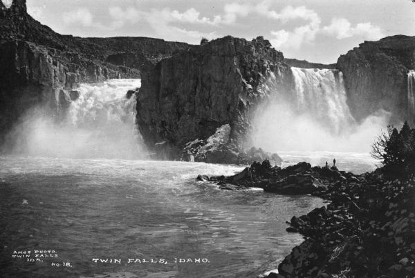 Elevated view of the falls. Two people stand on the rocks near the falls. Caption reads: "Twin Falls, Idaho."