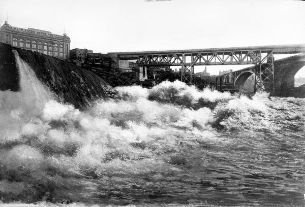 View of the Lower Falls on the Spokane River. A building on the left has a sign that reads: "Washington Water Power Company."