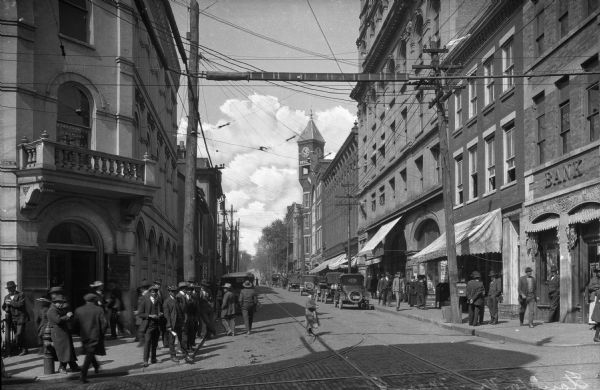 View of a busy downtown street. Pedestrians gather near Augusta National Bank on the street corner at right.