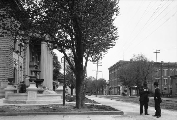 View down East Mansfield Street. On the left corner, two men stand near the neo-classical Crawford County Courthouse building, completed in 1908. The courthouse was assigned to architect Harlan Jones, and contractor A.E. Hancock.