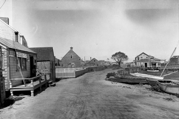 General view of town streets, with a harbor and early American store exteriors.