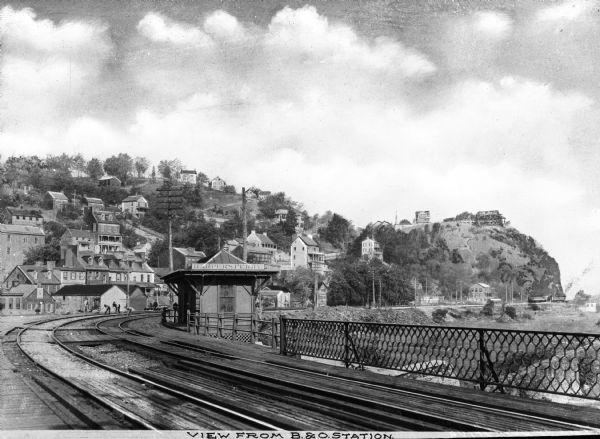 View from the Baltimore and Ohio Railroad Station, established in 1830.  The city's dwellings and establishments can be seen on a hillside from the railroad tracks in the foreground.