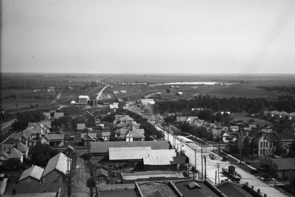 Elevated view looking out across town buildings to a plain beyond. The Hill County Jail can be seen to the right of the main street; it was constructed in 1893 and designed by W.C. Dodson.