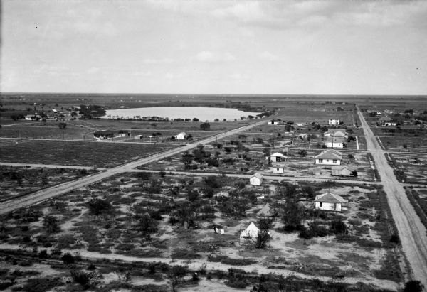 General view of sparsely inhabited country featuring a flat plains area and small lake.