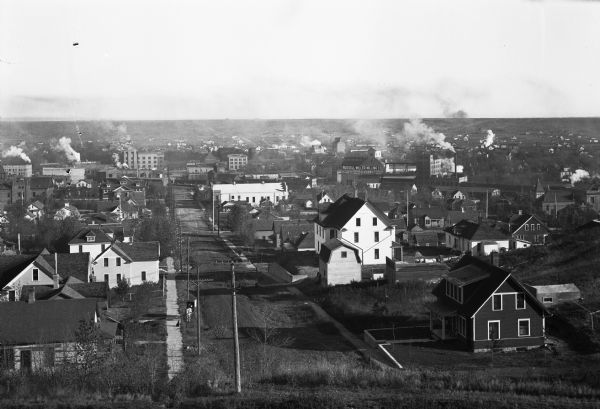 View of a town from an overlooking hill. Beyond dwellings, the Russell-Miller Milling Company is visible; it was built in 1906.