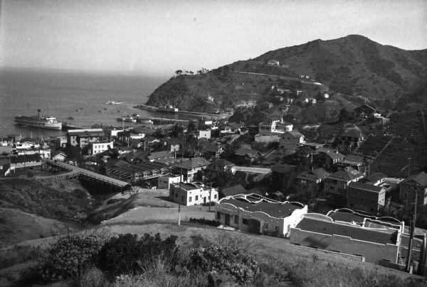 Elevated view of a town located along a hilly shoreline.