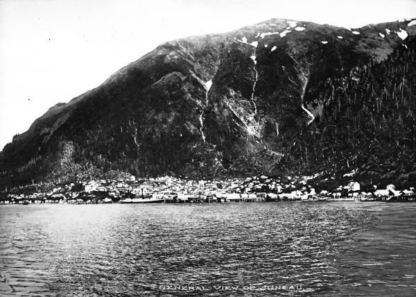 Distant view of a city from the opposite shore.  The city's buildings can be seen against a mountainside.