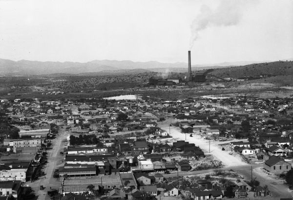 Elevated view of the city with a smokestack in the distance.