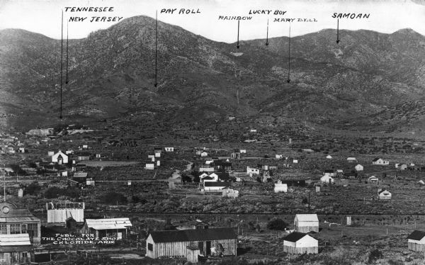Elevated view of a town with silver-lead-zinc mine locations marked in the hills in the distance. Published for The Chocolate Shop.