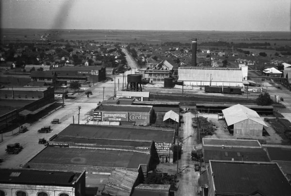 Elevated general view of an industrial area.  Automobiles drive down the road past stores and factories.