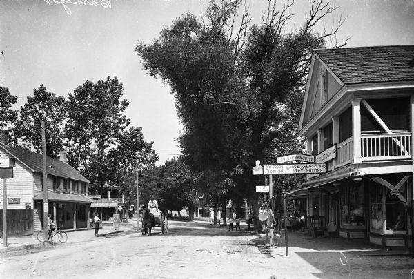View down the main street of town, lined with small shops.  A horse leads a wagon past Lewis Abramowitz' store at right.