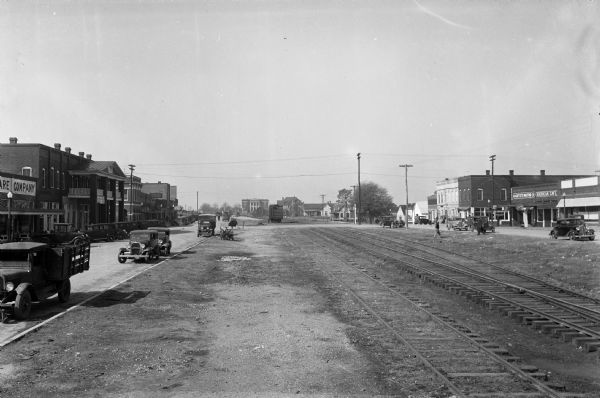 Commercial buildings stand on either side of a set of railroad tracks.  Automobiles line each street and the Toombs County Courthouse, featuring a colonnaded facade, is visible in the distance.  The courthouse was built in 1906, and rebuilt in 1919 after a fire in 1917.