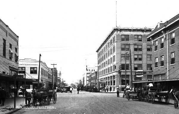 View of the business section of town. The street is lined with businesses including the National Bank of Commerce, a hotel, and a clothing store. Text on the photograph reads, "The Miller Drug Store, Thornberry & Shaw, Prop's."
