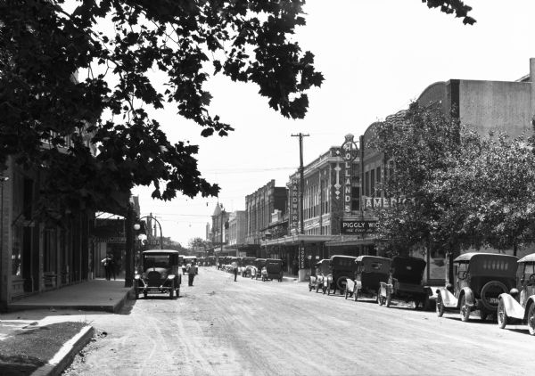 View down a city street, lined with storefronts.  Piggly Wiggly is visible at right; it was founded in 1916.