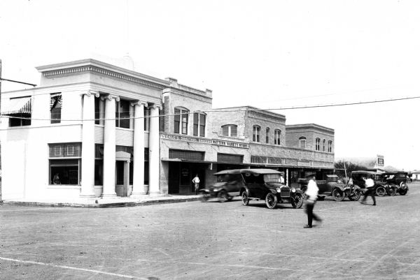 VIew down a city block featuring storefronts and Planters State Bank on the corner. The colonnaded building housed the bank from 1917 to 1924.