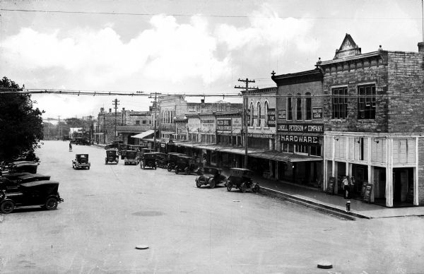 General view of a town street with storefronts. The building on the right corner bears a date of 1893.