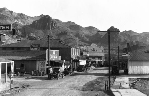 View down a street featuring a garage and Hotel Durlin, a stage depot. Landforms rise in the background.