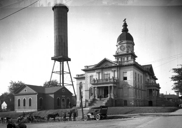 View of Athens City Hall, built in 1903-1904, featuring a central dome and clock tower. A water tower can be seen beyond the city jail to the left.