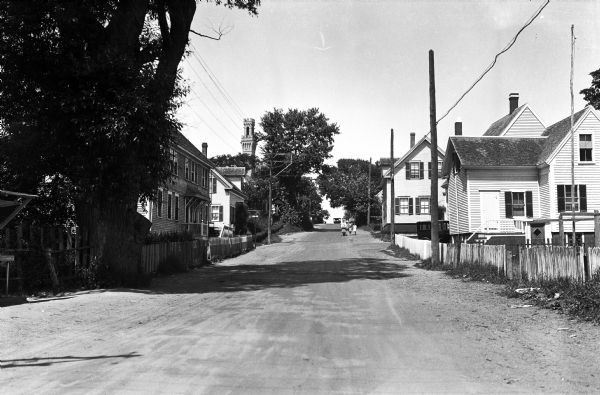 View down a residential street with 'Cape Cod' architecture.  The Pilgrim Monument, built between 1907 and 1910, looms in the background.