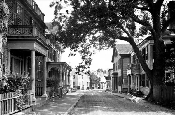 View down West Main Street, a narrow road lined with closely-set homes.  The Studley House stands at right, built around 1850 as the Captain Tristram P. Ripley House.