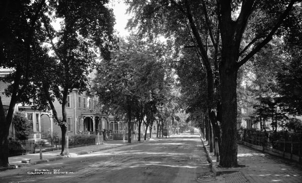 View down a tree-shaded residential street.  Published by Clinton Bowen.