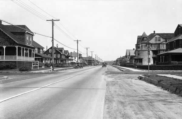 View down Main Avenue, a residential street lined with homes. Arthur Holford Contractor & Builder stands on the left.