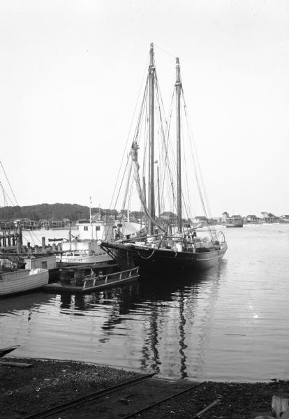 A sailboat and other fishing boats moor in the harbor.
