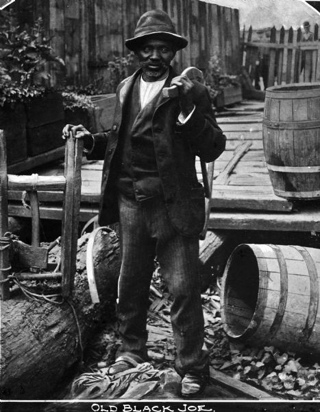 Sculpture of a man near a wooden deck and barrels. Caption reads: "Old Black Joe."