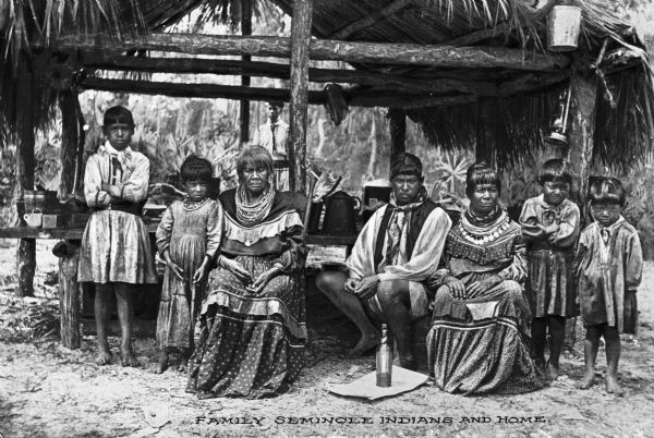 Group portrait of a Seminole Indian family near a hut.