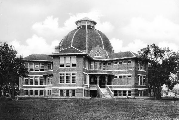Exterior of Uvalde High School, founded in 1891.  The brick building features a central porch and dome.