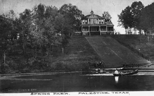 View of a man in a horse-drawn carriage and a another in a boat before  Spring Park, a large residence at the top of a hill.  Published by Louis Durr & Son.
