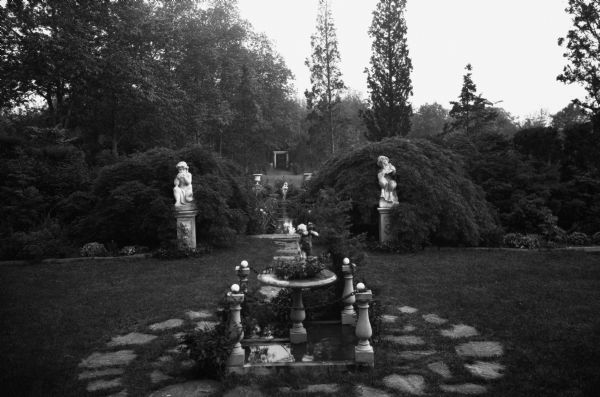 View of the gardens at the estate of Ernest L. Conant, featuring sculptures and a fountain.