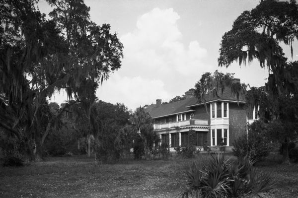 Exterior of the residence of Mr. J.A. Albright.  The brick home can be seen amidst foliage.