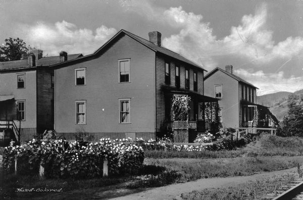 View of a group of similarly designed houses in a residential area. There are railroad tracks on the right.