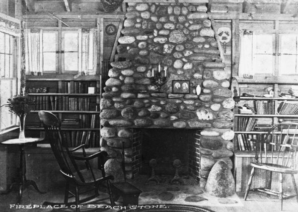 Interior view of a home featuring a fireplace composed of beach stone, flanked by bookshelves.