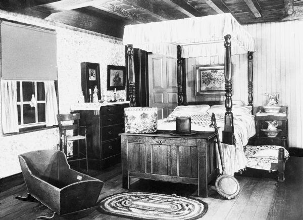 Interior of Judson House, built by Captain David Judson in 1750. The bedroom features a four-poster bed and a baby cradle.