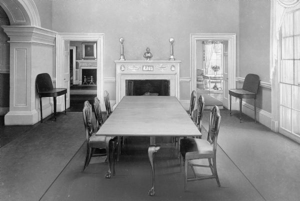 Interior view of the dining room at Monticello, residence of Thomas Jefferson, built in 1772.  A long dining table leads to a fireplace flanked by two doorways.