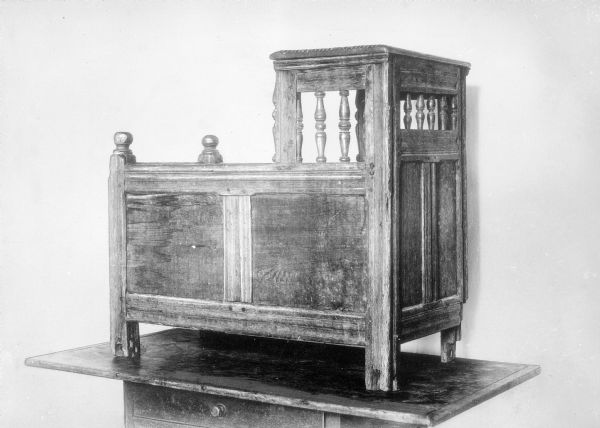 View of the Fuller Cradle, built in Duxbury, Massachusetts between 1680 and 1720.  Constructed out of maple and white pine, the cradle features handcrafted spindles and paneling.