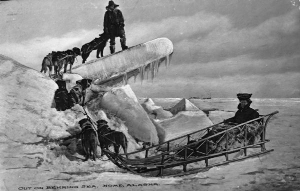 View of a dogsled with a female passenger, with the driver posed on a large formation behind her..