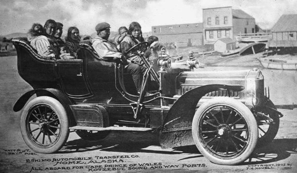 Side view of an a large group of people in an automobile from the Eskimo Automobile Transfer Company heading toward Cape Prince of Wales and Kotzebue Sound. Copyright 1905 by F.H. Nowell. Published by Watt & Bryant.