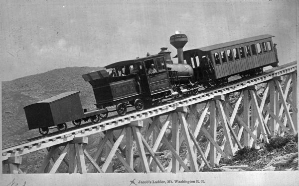 View of a railroad engine with passengers before it ascends Mount Washington Railroad's 'Jacob's Ladder,' built around 1868 with a grade of 37.41%.