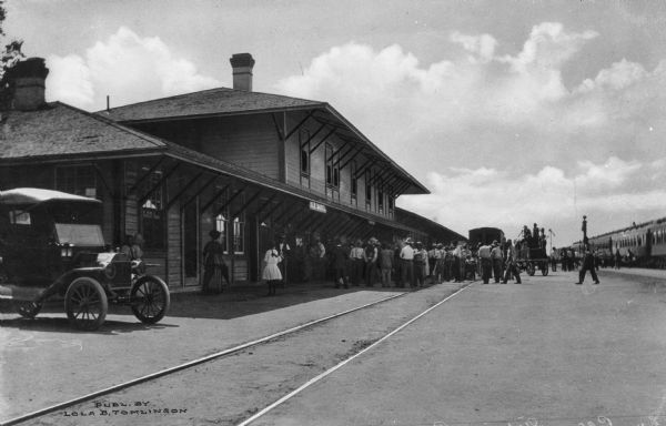 View down railroad tracks of passengers arriving at Southern Pacific Railroad Station, built around 1880. Published by Lola B. Tomlinson.